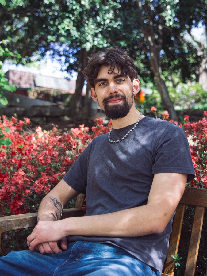 Nick Bentlage seated on a bench in front of flowers