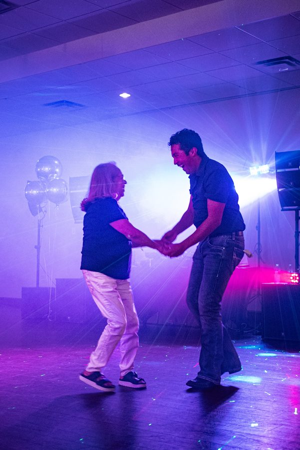 Two guests dancing on stage under colored lights at a graduation party
