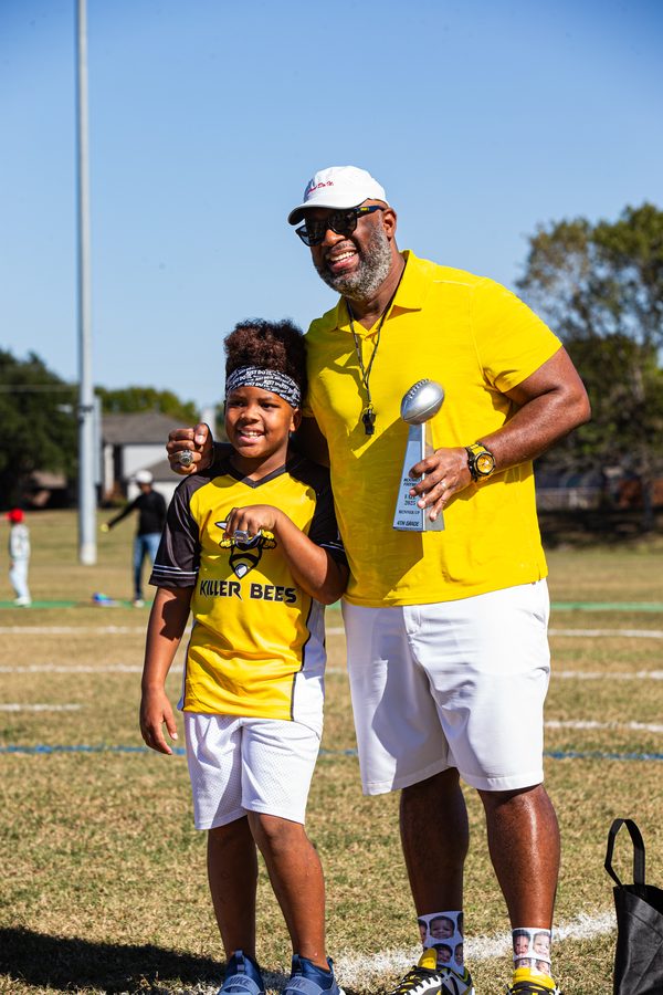 Flag football player and coach posing with a trophy